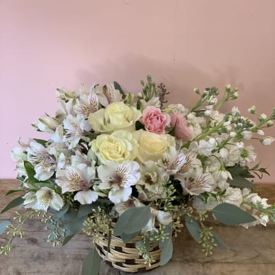 Basket arrangement of pale roses, white alstroemeria, and pink blooms