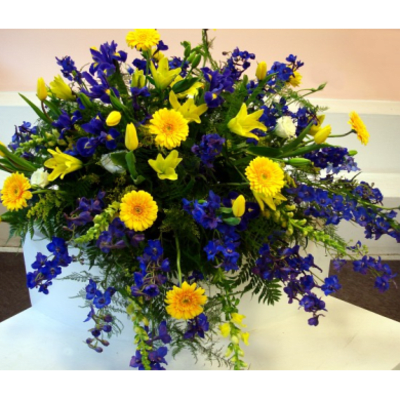 Large bouquet of yellow and blue flowers in a white container
