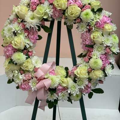 Heart-shaped floral wreath with pale roses, pink blooms, and a pink ribbon