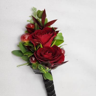Red rose boutonniere with berries and greenery on a black wrapped stem