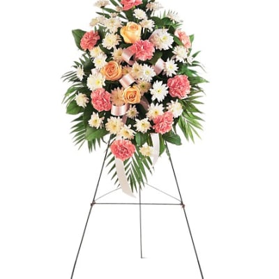 Standing floral spray with pink carnations, peach roses, and white daisies on an easel