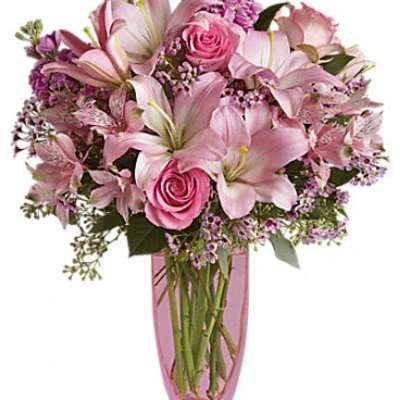 Pink lilies and roses arranged in a pink vase