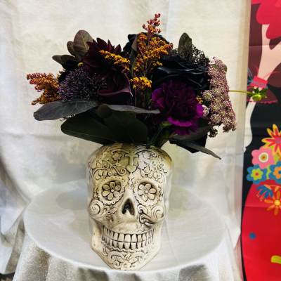 Dark floral arrangement in a decorative skull vase