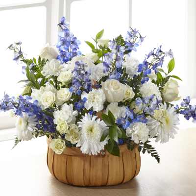 Basket arrangement of white roses, carnations, and daisies with blue delphinium.