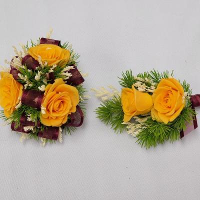 Yellow rose boutonnieres with burgundy ribbon and greenery