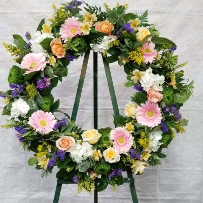 Floral wreath on a stand with pink, white, yellow, and purple flowers