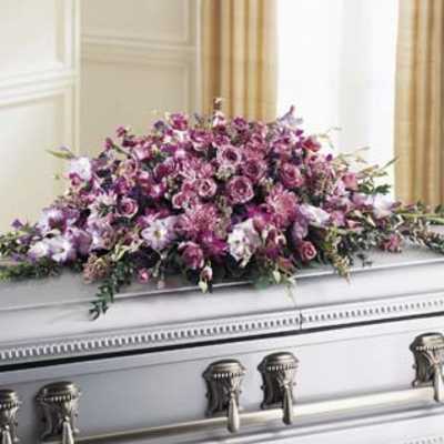 Lavender and pink mixed-flower casket spray in a long cascading design on a silver casket.