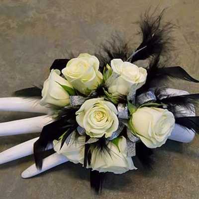 White rose bouquet with black feathers and silver ribbon on a mannequin hand