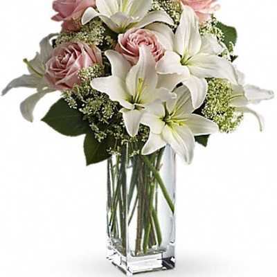 Pink roses and white lilies arranged in a clear glass vase