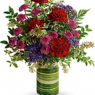 Bouquet of red carnations and purple flowers in a green glass vase