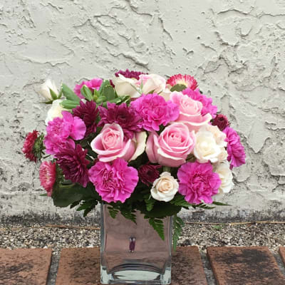Pink and white roses with carnations in a clear glass vase