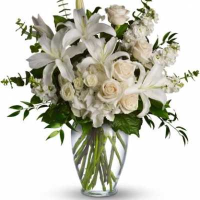White lilies and roses arranged in a clear glass vase