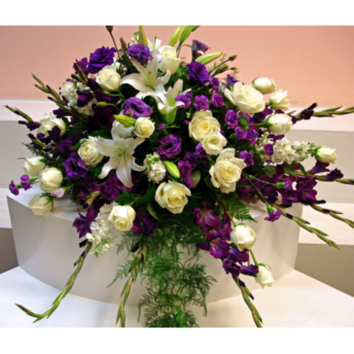White lilies and cream roses with purple flowers in a large arrangement