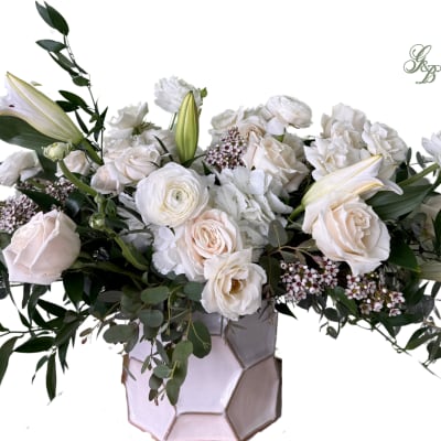 White floral arrangement in a geometric vase with roses and lilies
