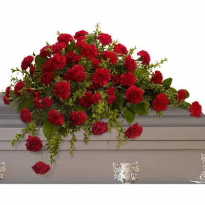 Red carnation arrangement draped over a gray casket