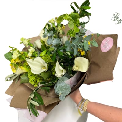 Bouquet with white calla lilies and green flowers wrapped in brown paper