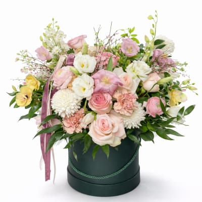 Pastel flower arrangement in a dark round box