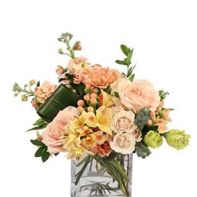 Peach and cream flower arrangement in a clear square vase