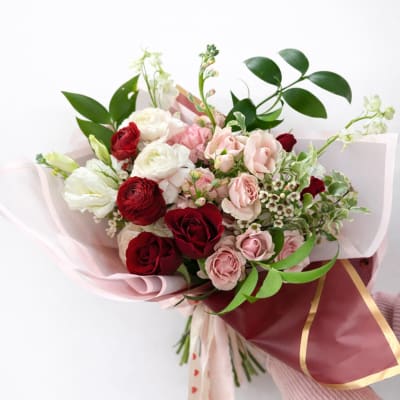 Bouquet of red, pink, and white roses wrapped in pink paper