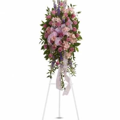 Tall pink and lavender standing spray with roses and accent blooms on a white easel.