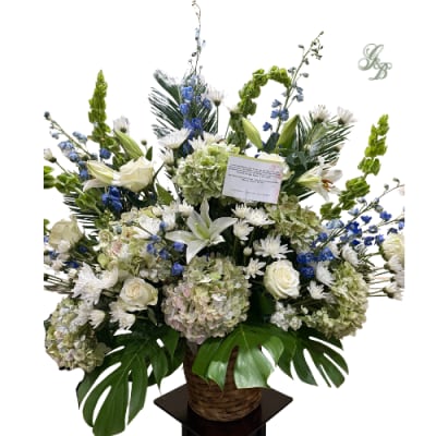 Large white and blue floral arrangement in a wicker basket