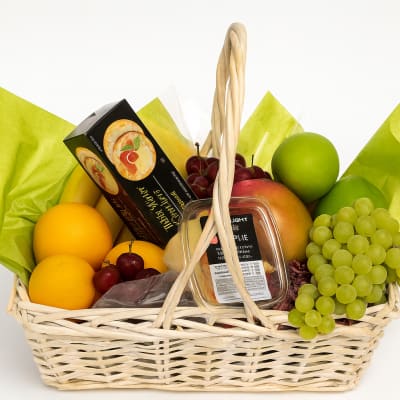 Fruit basket with oranges, grapes, apples, and packaged snacks