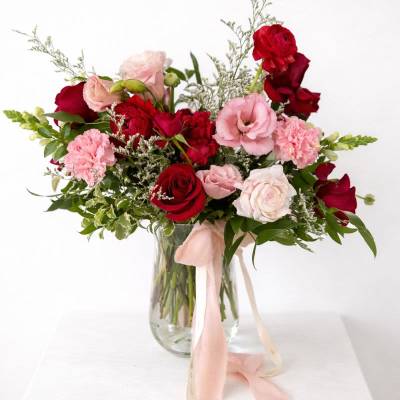 Bouquet of red and pink roses in a glass vase with a pink ribbon