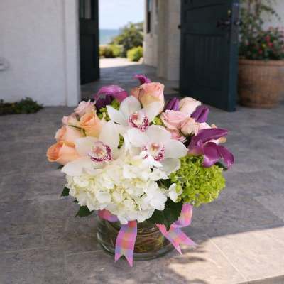 Bouquet of white orchids, pink roses, and green hydrangea in a glass vase