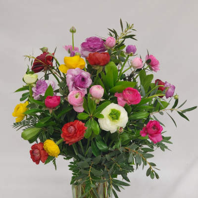 Mixed bouquet of colorful ranunculus in a clear glass vase