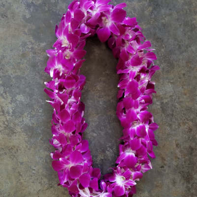 Magenta orchid lei on a gray stone surface