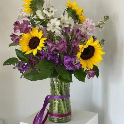 Bouquet of sunflowers, purple and white flowers in a glass vase