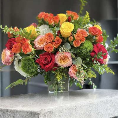 Mixed roses in a clear glass vase with greenery