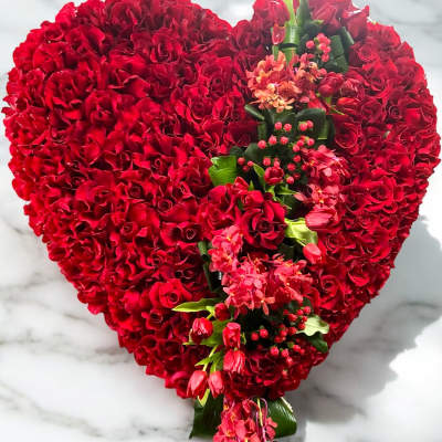 Heart-shaped red rose arrangement with pink flowers and greenery