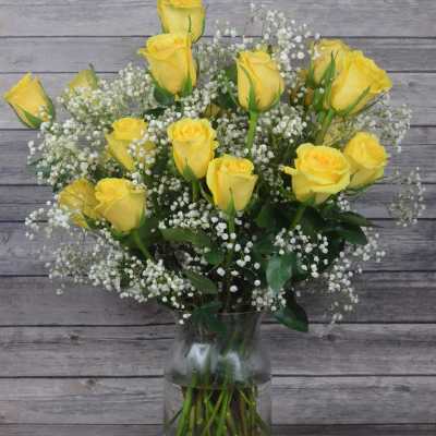 Yellow roses in a clear glass vase with white baby's breath