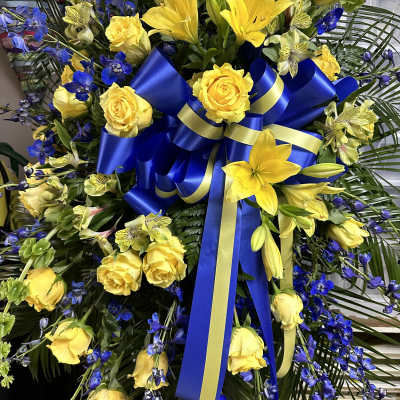 Yellow roses and lilies with blue flowers and a blue ribbon