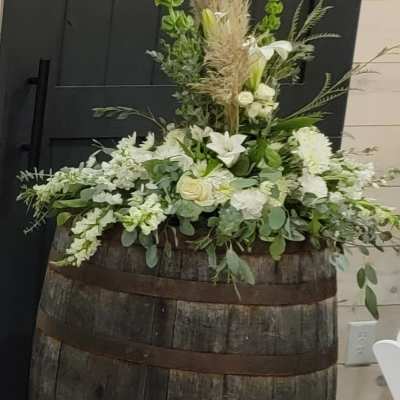 White floral arrangement in a wooden barrel with tall grasses