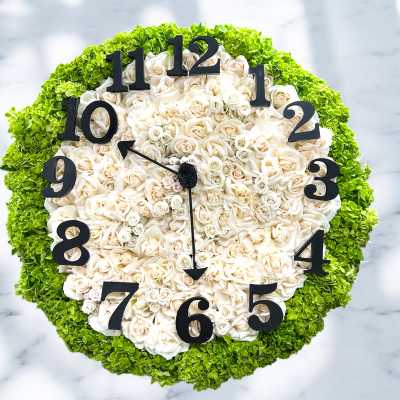 Round floral clock made of white roses with green edging and black numbers