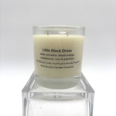 Cream-colored scented candle in a clear glass jar labeled Little Black Dress on a clear stand