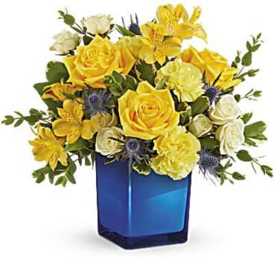 Yellow and white flower arrangement in a blue glass vase
