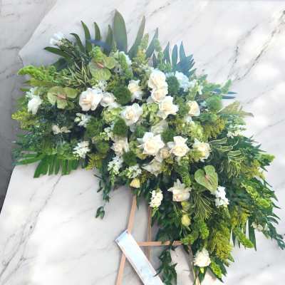 Large white and green floral standing spray on an easel
