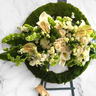 Cream and green funeral wreath with roses and calla lilies