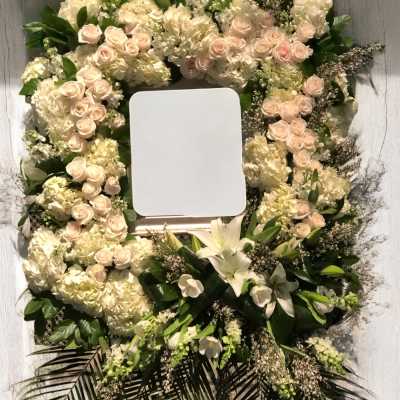 Floral wreath with pale roses, hydrangeas, and white lilies around a blank center panel