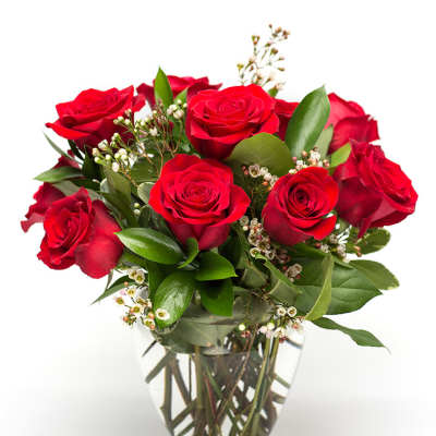 Red roses arranged in a clear glass vase with small white filler flowers