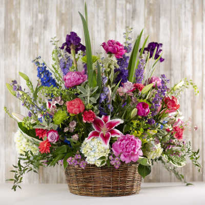 Mixed bouquet in a wicker basket with pink, purple, and white flowers