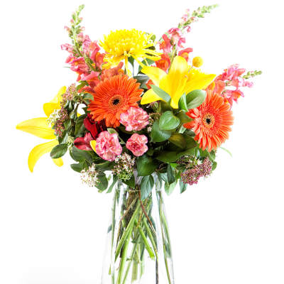 Bright mixed bouquet with yellow lilies and orange gerbera daisies in a glass vase