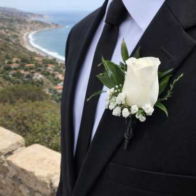 White rose boutonniere on a black suit jacket