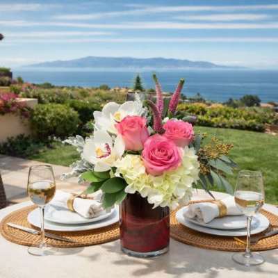 Pink and white floral centerpiece in a glass vase on an outdoor table