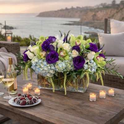 Purple and white floral centerpiece on a table with candles and wine glasses