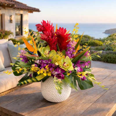 Tropical flower arrangement in a white textured vase on a wooden table