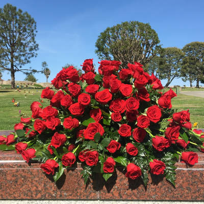 Large bouquet of red roses arranged on a stone memorial ledge